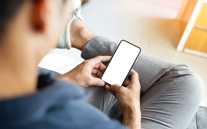 スマホでカーリースを探す男性